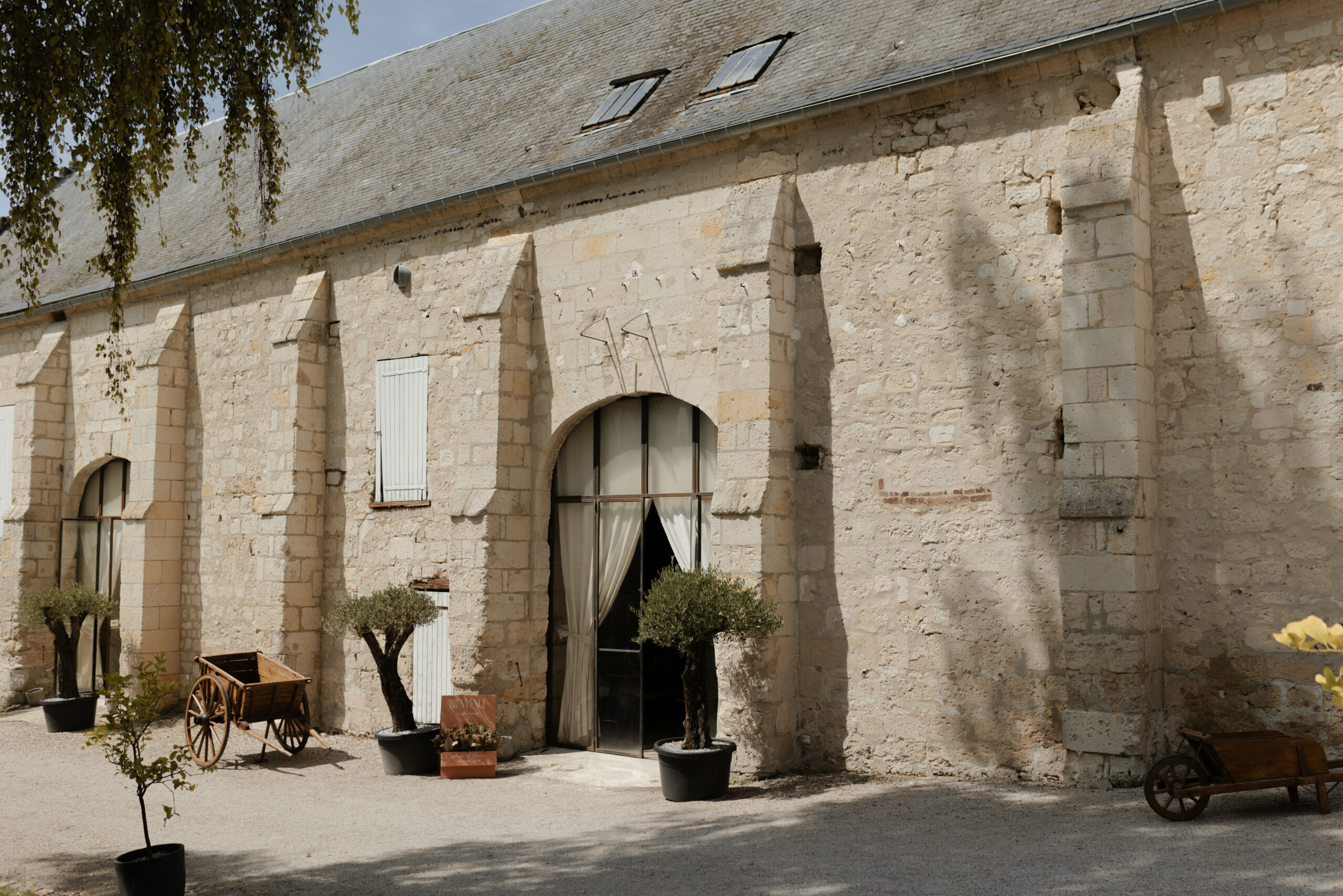 Façade et entrée de la grange de réception en pierre blanche au domaine Les Pommerieux.