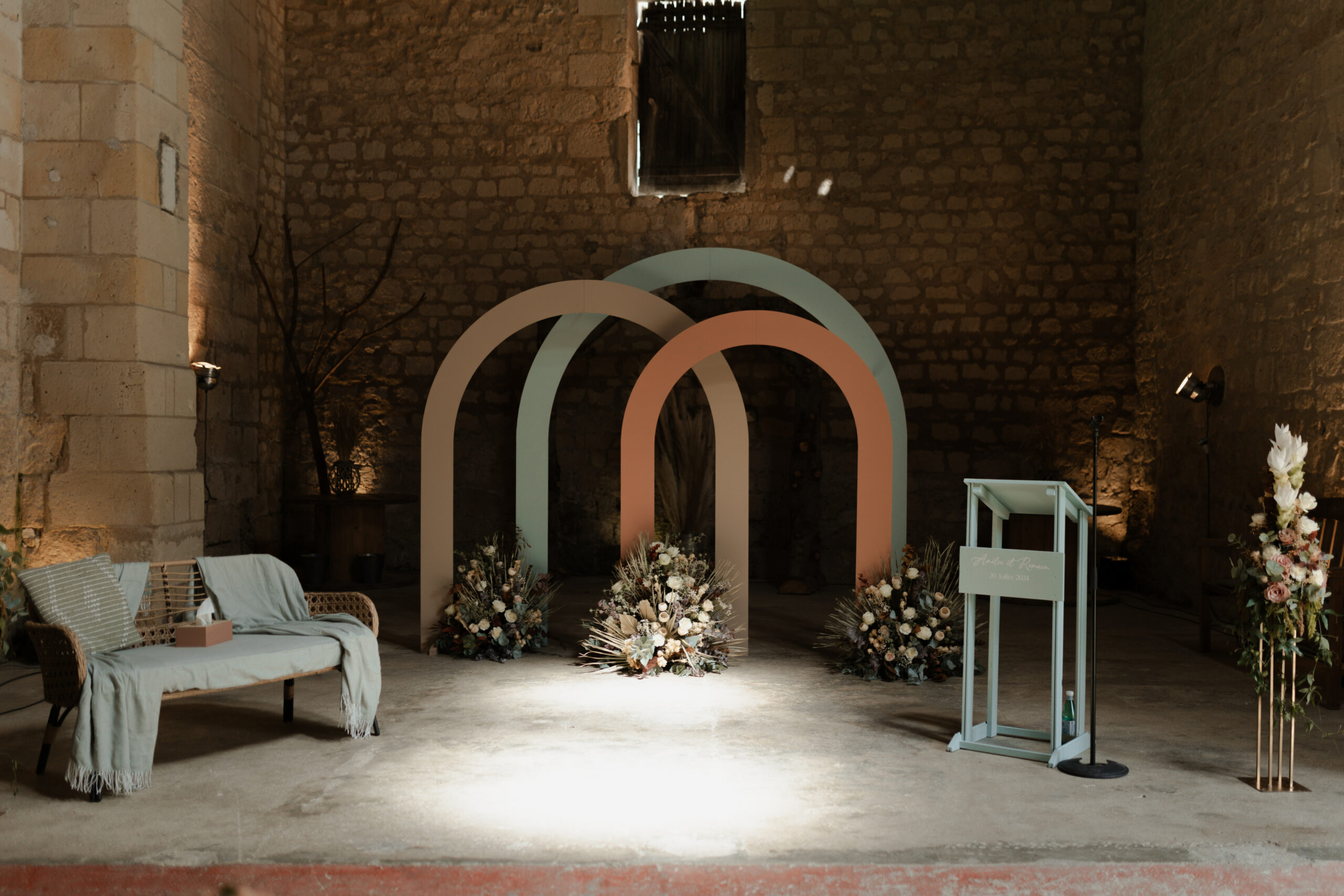 Arche de cérémonie laïque colorée à l'intérieur de la grange des Pommerieux, éclairée par un puits de lumière.