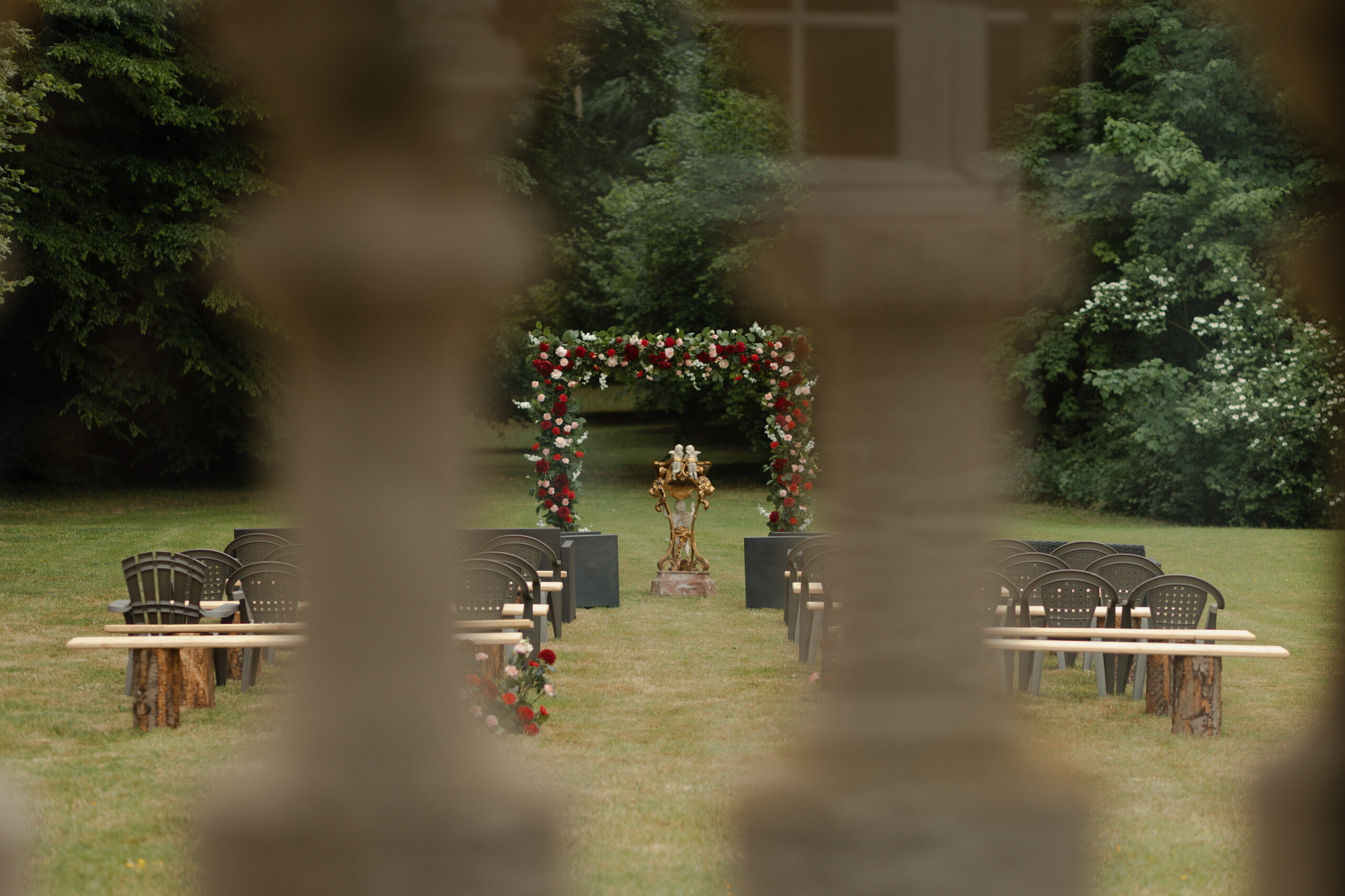 Cérémonie laïque au Château de Montaubois, arche florale rouge et blanche prise entre deux colonnes.