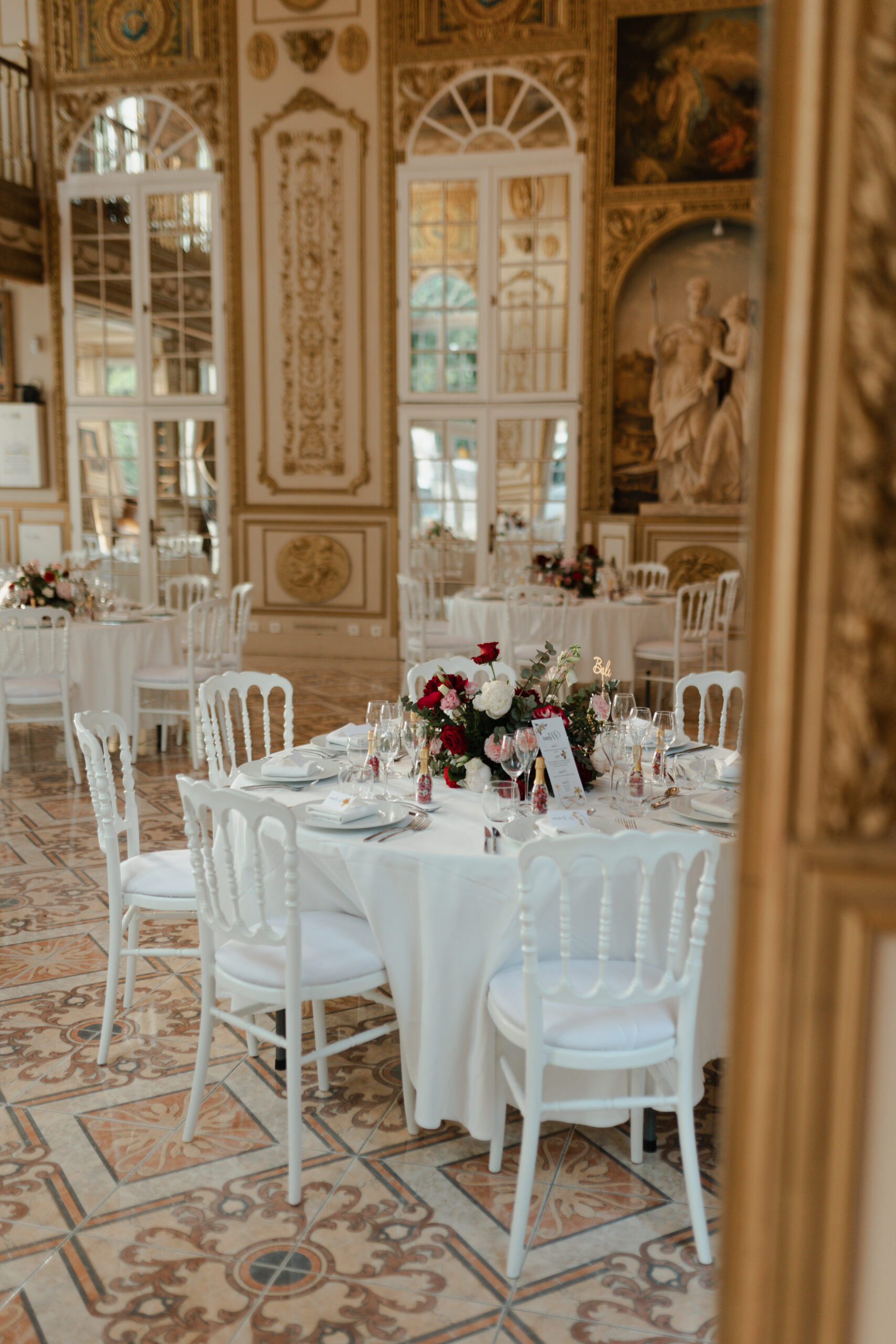 Reflet d'une table de banquet de mariage dans le miroir doré du Château de Montaubois.