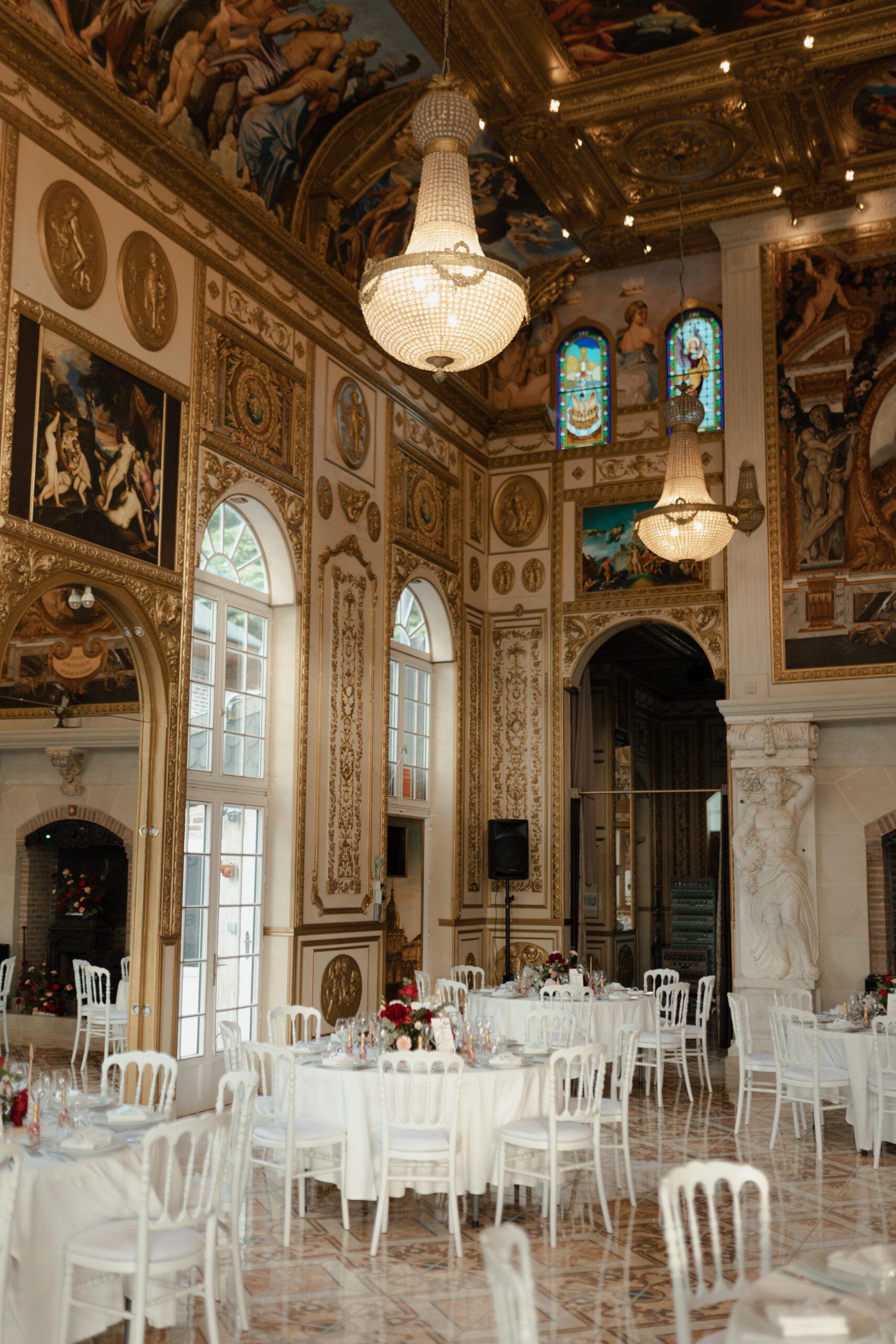 Photo portrait de la salle : hauteur immense, lustres, dorures et fenêtres arrondies.