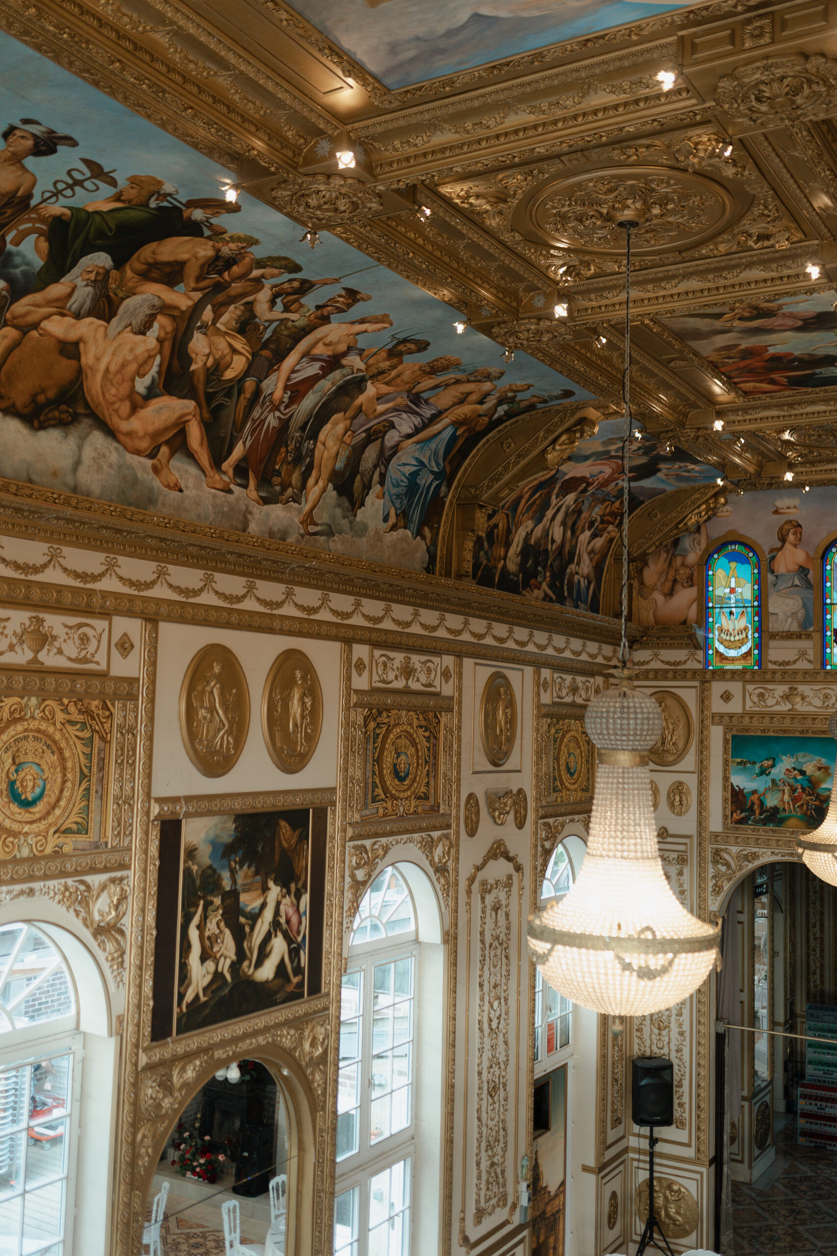 Gros plan sur une fresque murale et un lustre en cristal dans la salle de réception du château.