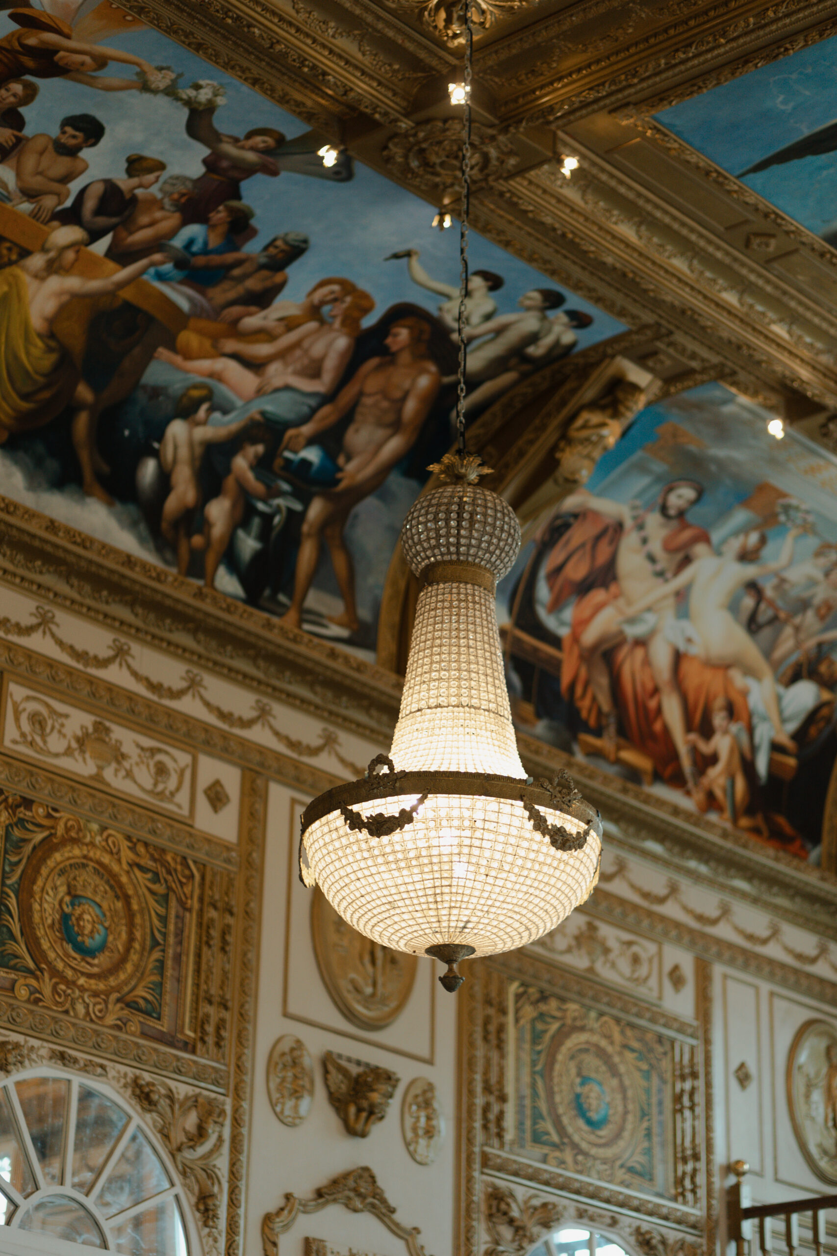 Lustre en cristal luxueux devant un plafond peint en fresque au Château de Montaubois.