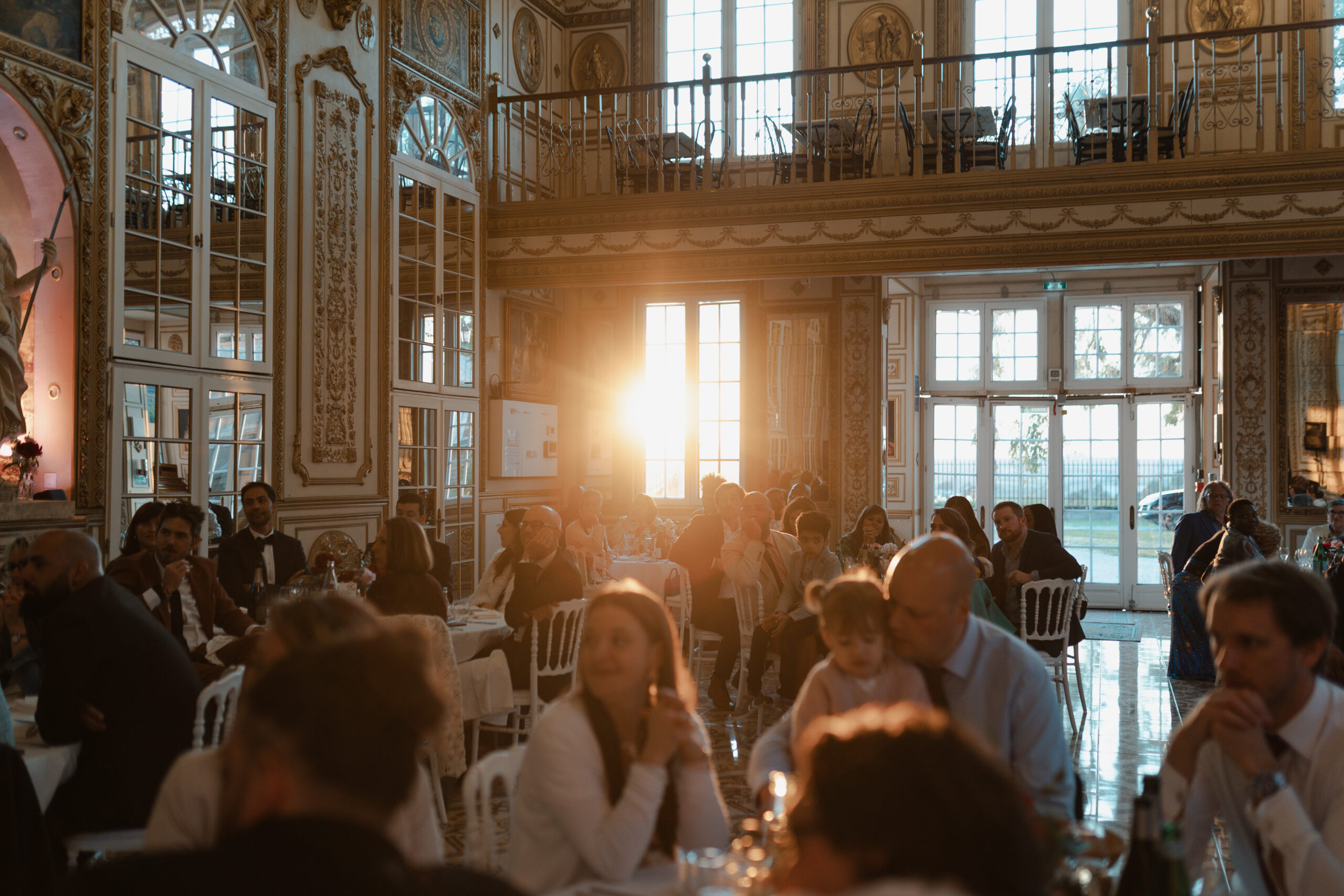 Dîner de mariage au Château de Montaubois, rayon de soleil doré traversant la fenêtre de la salle dorée.