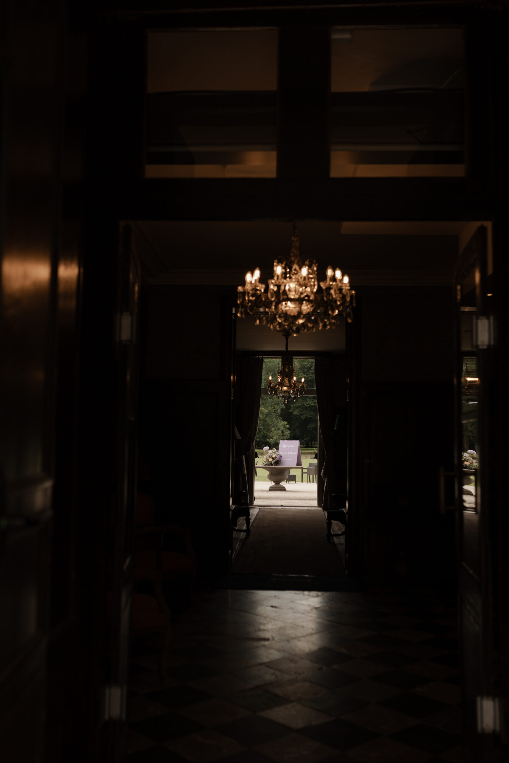 Vue depuis le hall sombre vers le parc lumineux avec panneau d'accueil de mariage.