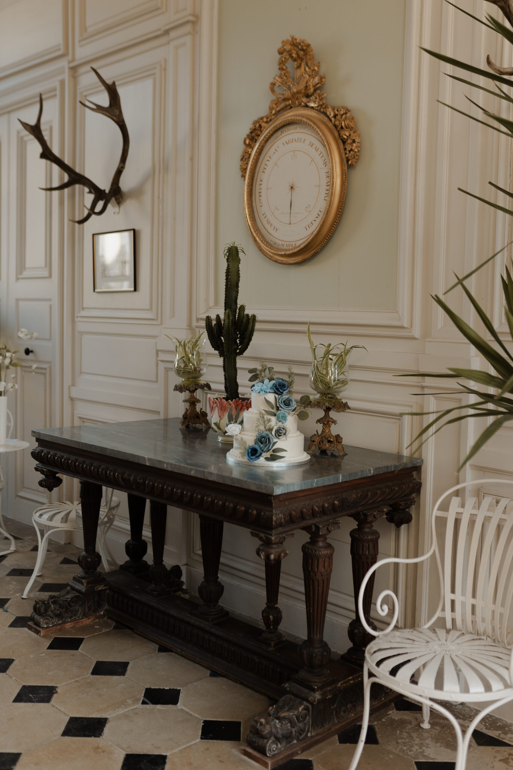 Hall d'entrée du Château de Juvigny avec gâteau de mariage, table ancienne, horloge de luxe et moulures aux murs.