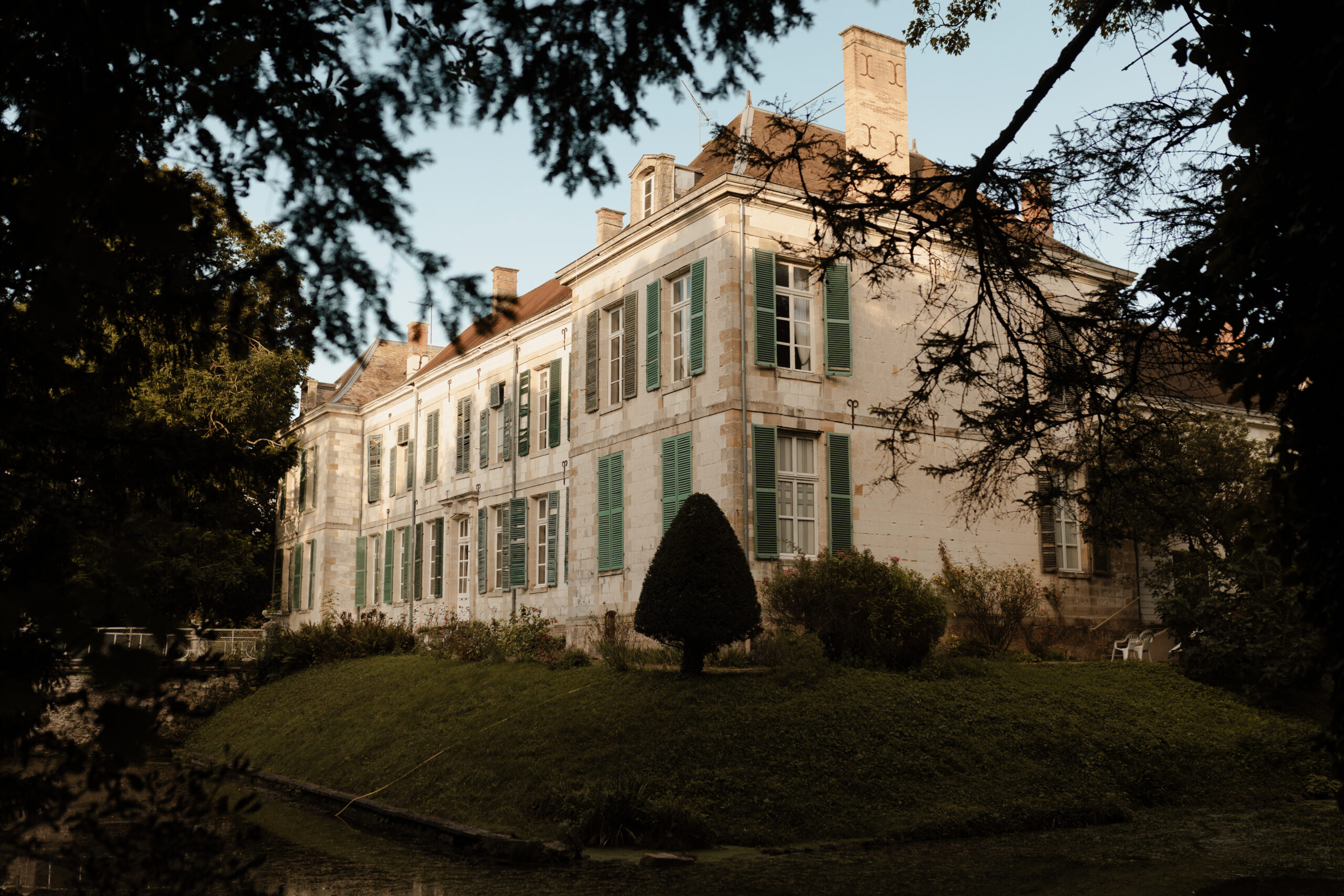 Vue de l'aile droite du Château de Juvigny avec le courant d'eau et la nature environnante mise en valeur.