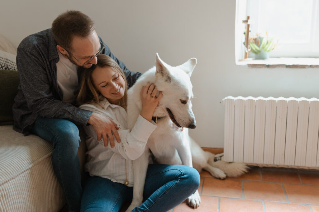 Séance grossesse lifestyle à Reims : futurs parents riant avec leur chien, plan large.