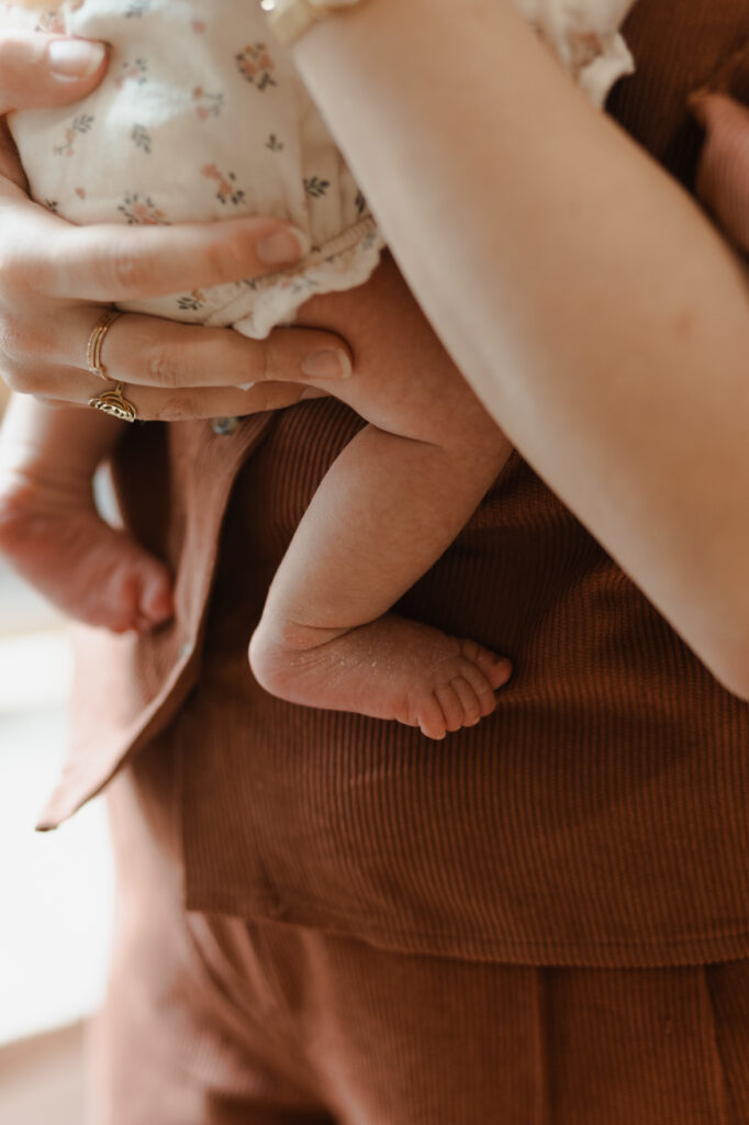 Plan macro des pieds nus de bébé tenus par maman lors d'une séance à Reims.