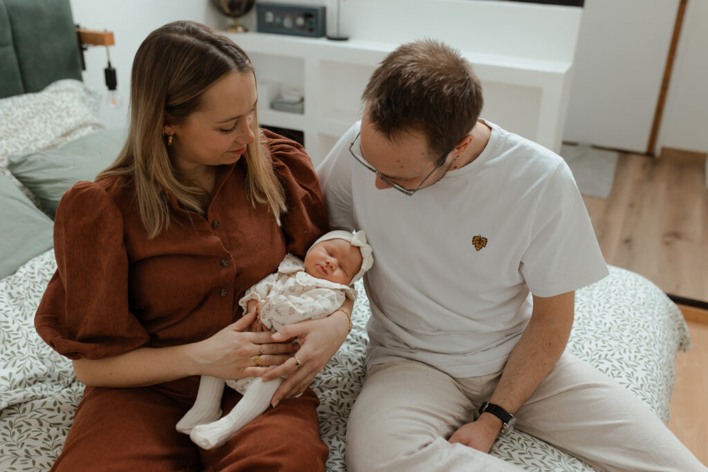 Parents assis côte à côte tenant leur nouveau-né entre eux avec tendresse à Reims.