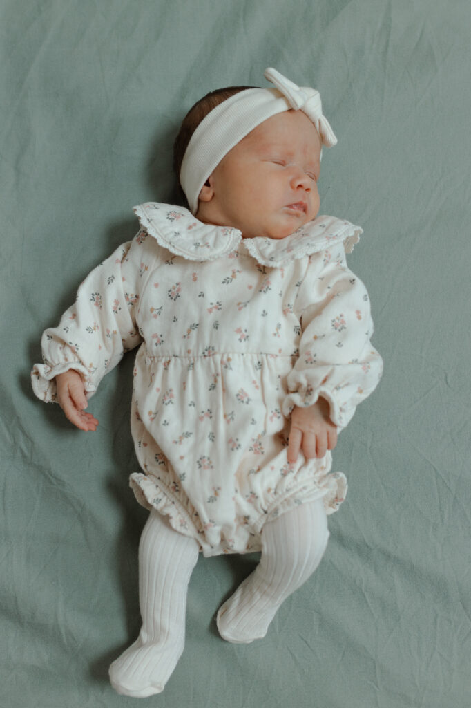 Nouveau-né allongé paisiblement sur un lit, séance naissance Reims.