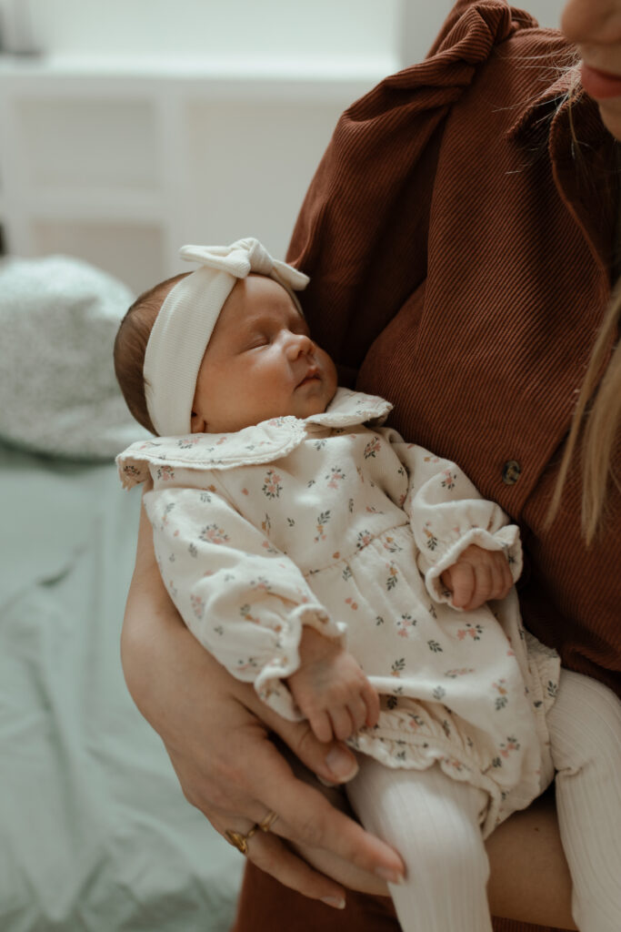 Bébé assoupi dans les bras de sa maman, séance photo Reims.