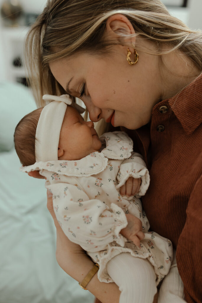 Portrait serré très attendrissant d'une maman souriante joues contre joues avec son bébé qui sourit aussi. Séance photo naissance à Reims.