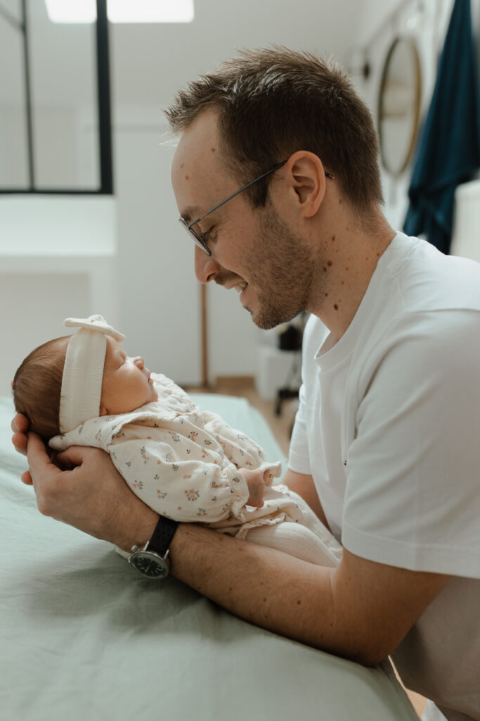 Papa contemplant son nouveau-né avec beaucoup d'amour, séance naissance.