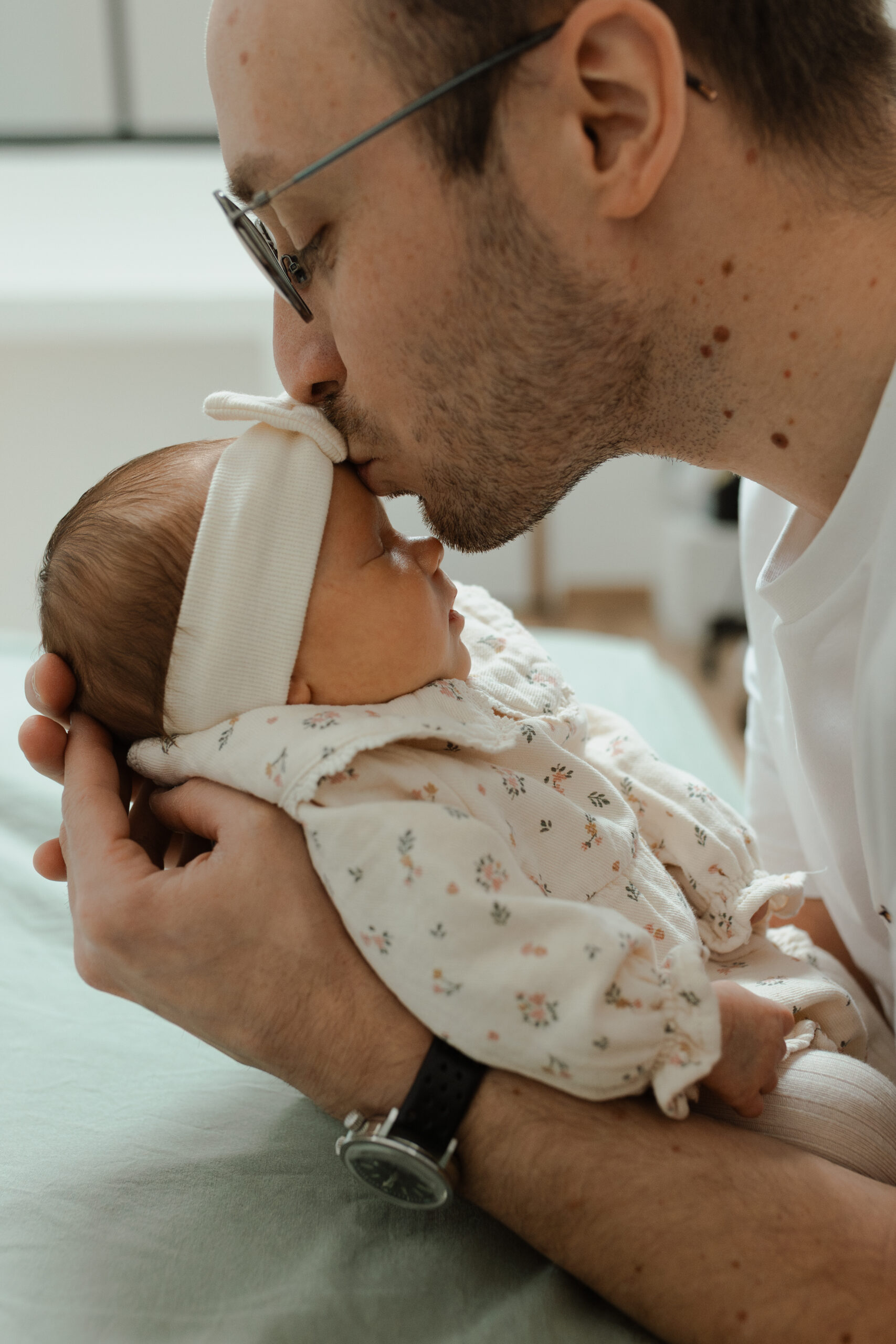 Papa déposant un baiser sur le front de son bébé, moment doux à Reims.