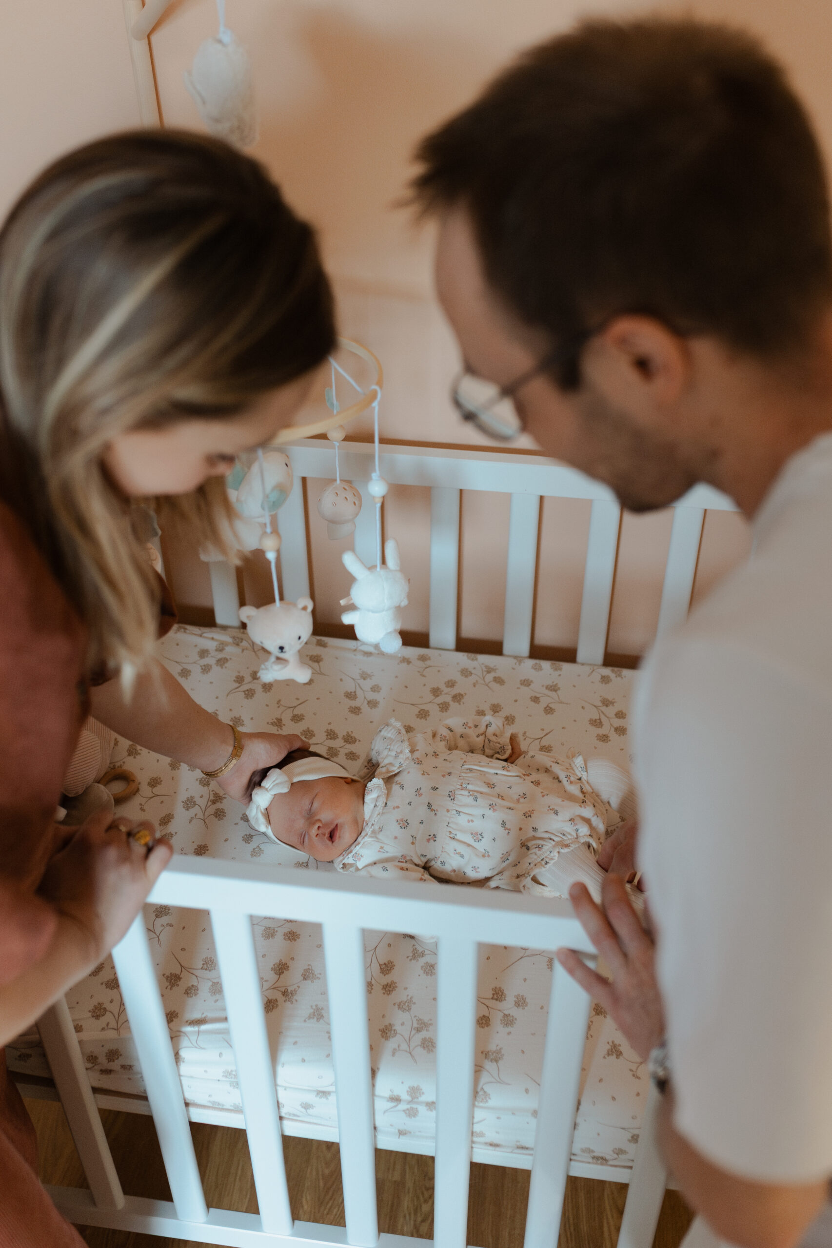 Bébé dans son lit avec parents en premier-plan, style artistique.