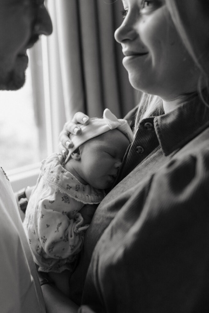Gros plan noir et blanc des parents face à face, bébé endormi contre la maman.